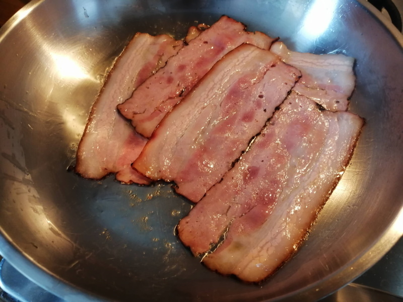 Na rozpálenú panvicu rozložíme plátky anglickej slaniny a opražíme z obidvoch strán.