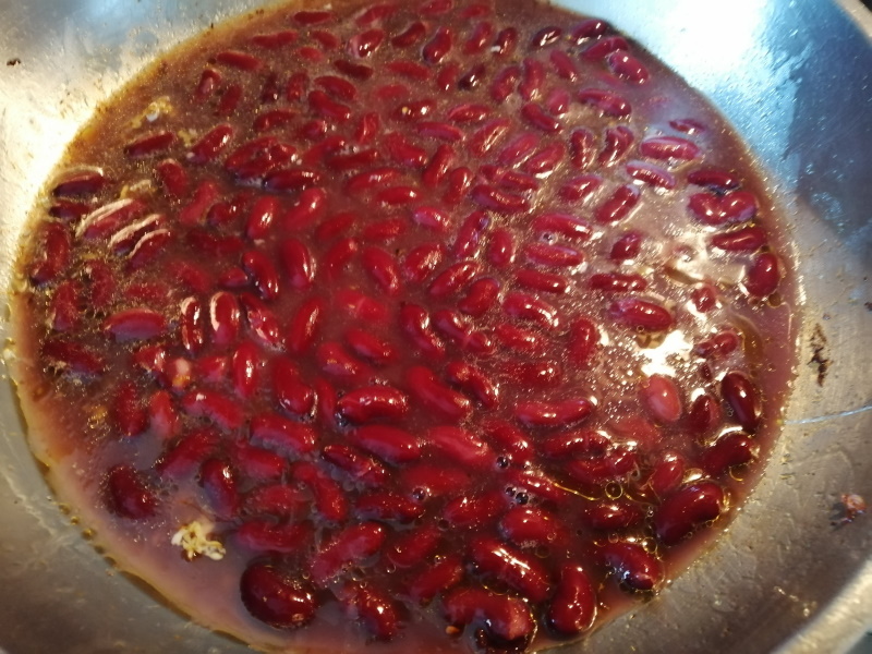 Hotové volské oká preložíme na servírovací tanier a do panvice vylejeme celú konzervu fazule v paradajkovej omáčke.