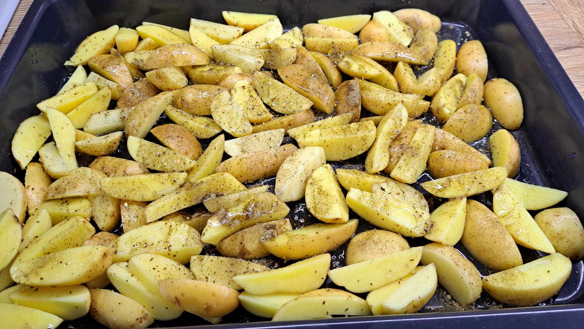 Zemiaky zlejeme, preložíme do pekáča, posypeme obľúbenou zmesou korenia na pečené zemiaky a polejeme olejom.