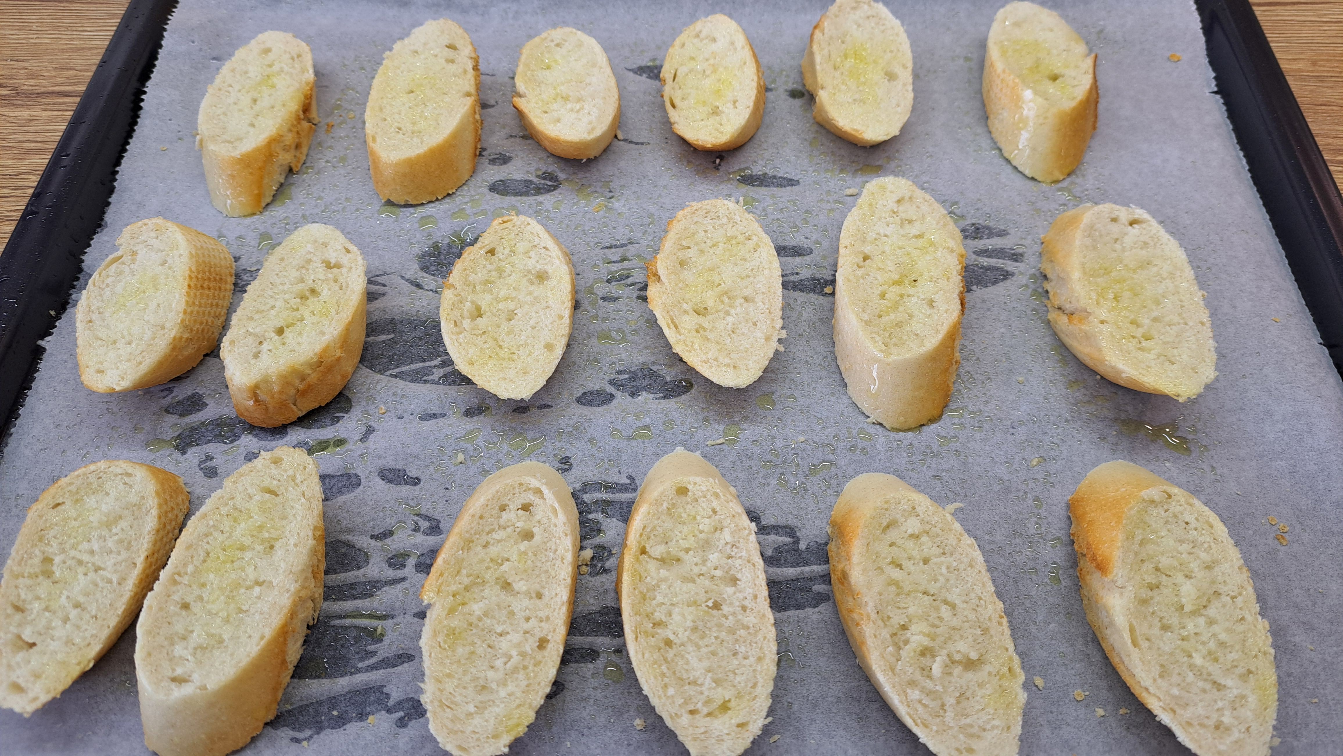 nakrájame si dve francúzske bagety na kolieska v dáme ich piecť na plechu vystlanom papierom na pečenie do rúry s grilom na 150 °C, aby sa vysušili