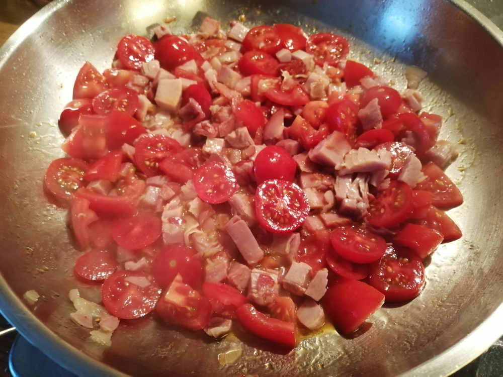 Keď sa začne šunka pražiť, pridáme nakrájané baby paradajky.