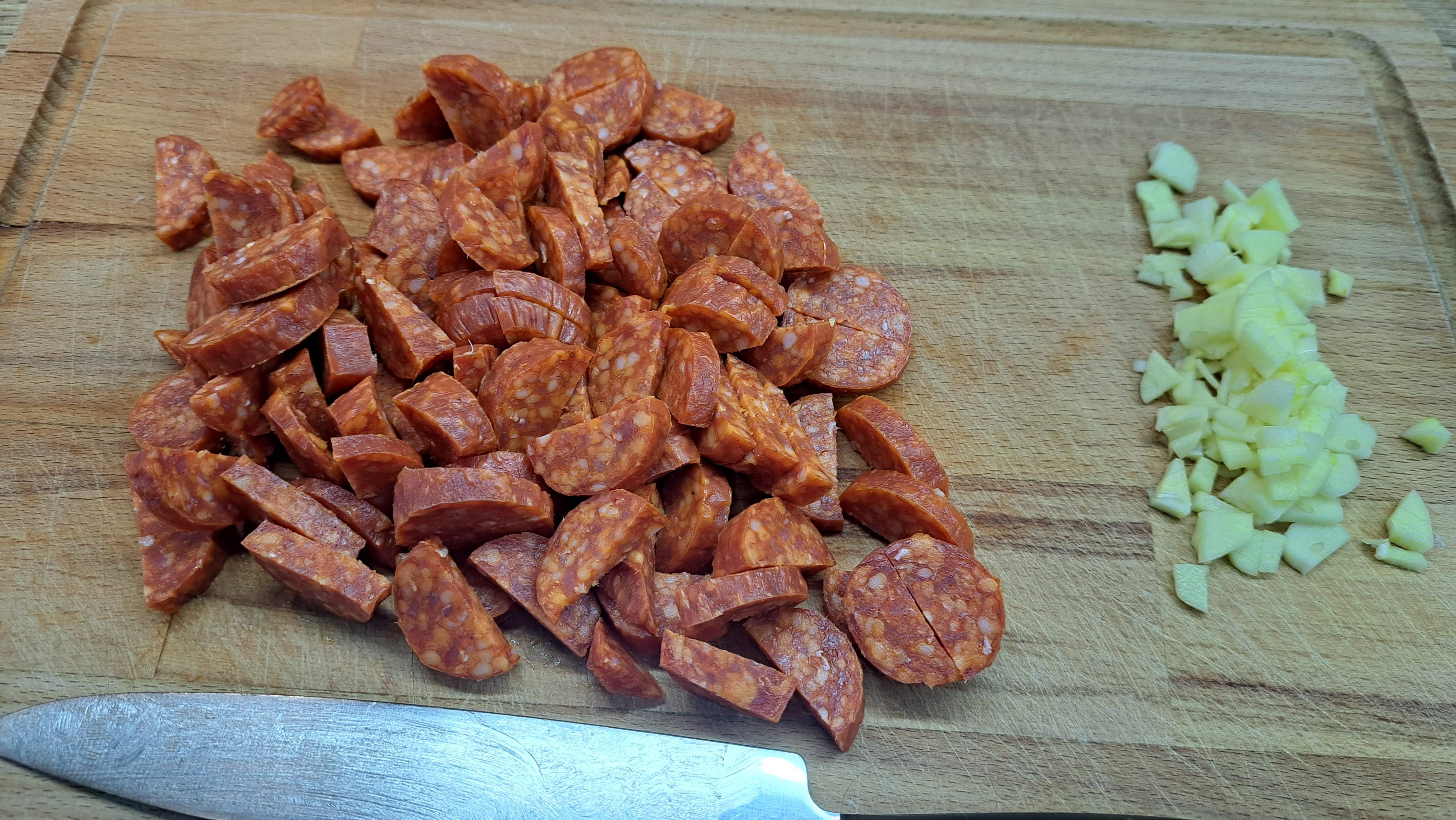 Klobásy si nakrájame po dĺžke na polovice a potom na mesiačiky. Cesnak nakrájame na drobné pásiky