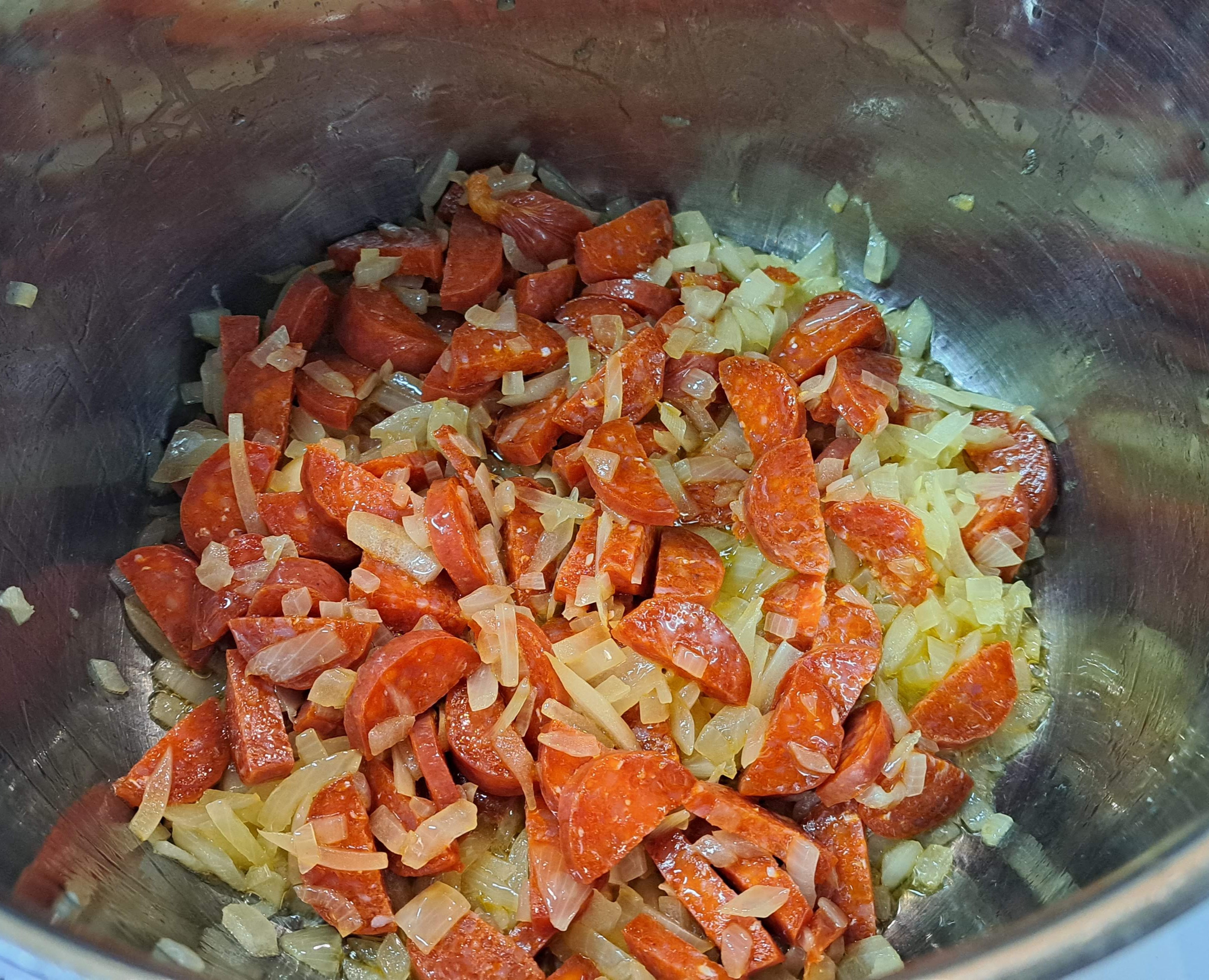 Do hrnca k cibuli pridáme nakrájané klobásy a spolu zarestujeme, aby pustila farbu a chuť