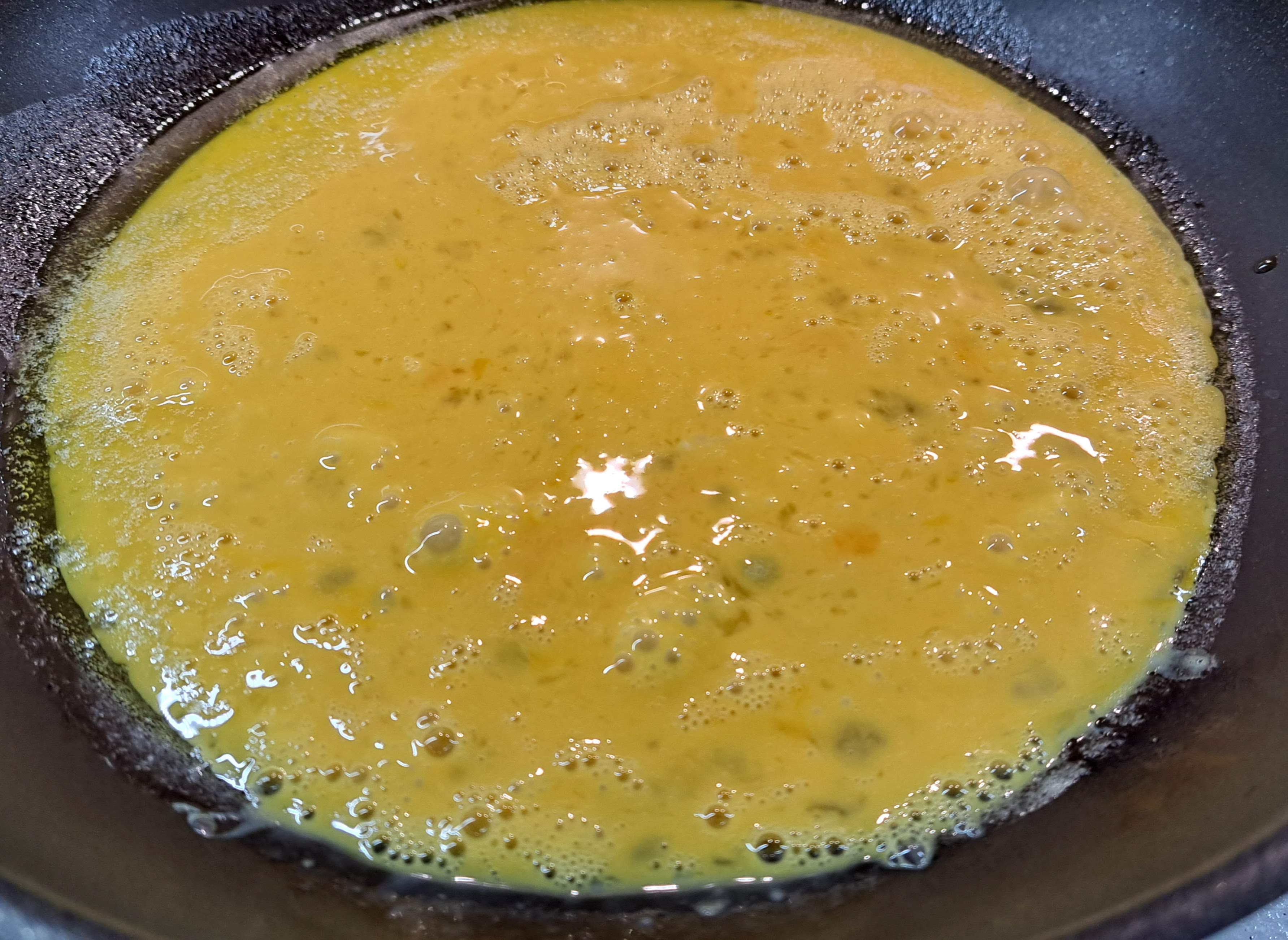 Rozšľahané vajcia z misky opatrne nalejeme na panvicu na rozpustené maslo na olivovom oleji