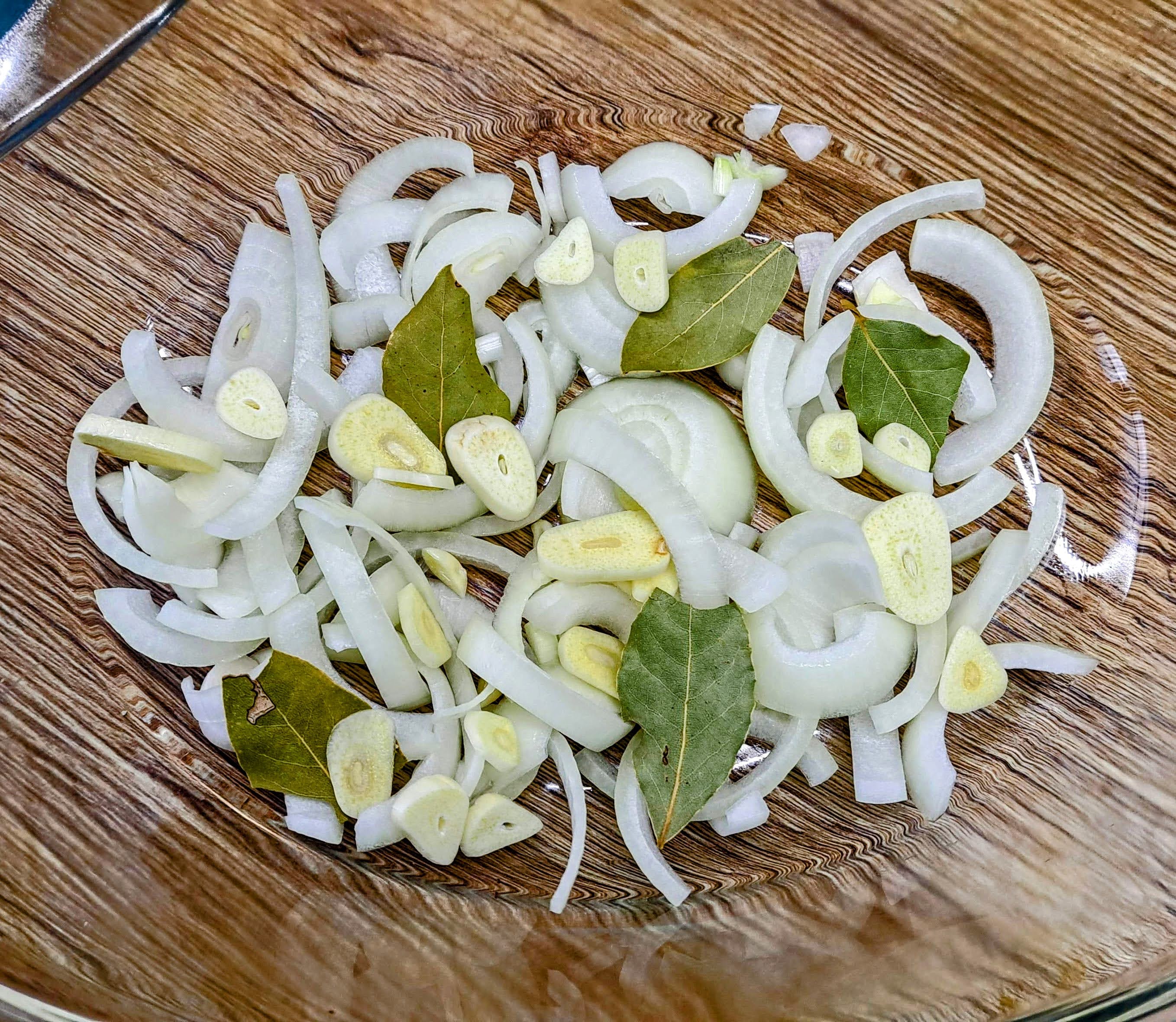 Zapekaciu misu vyložíme cibuľou nakrájanou na rezance, olúpanými strúčikmi cesnaku nakrájanými na plátky a bobkovými listami