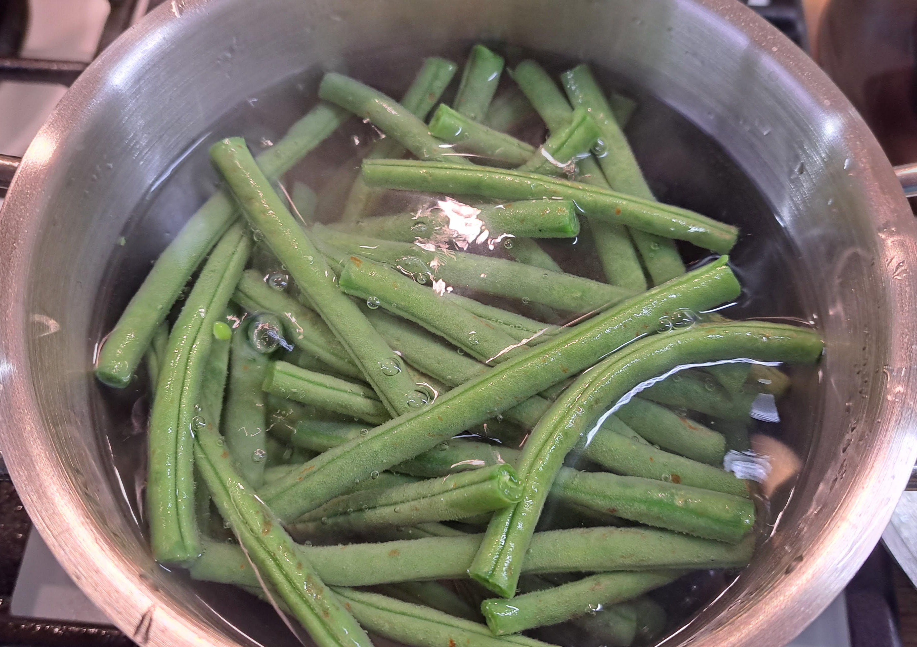 V hrnci dáme variť vodu s morskou soľou. Keď začne vrieť, vložíme do vody fazuľové struky