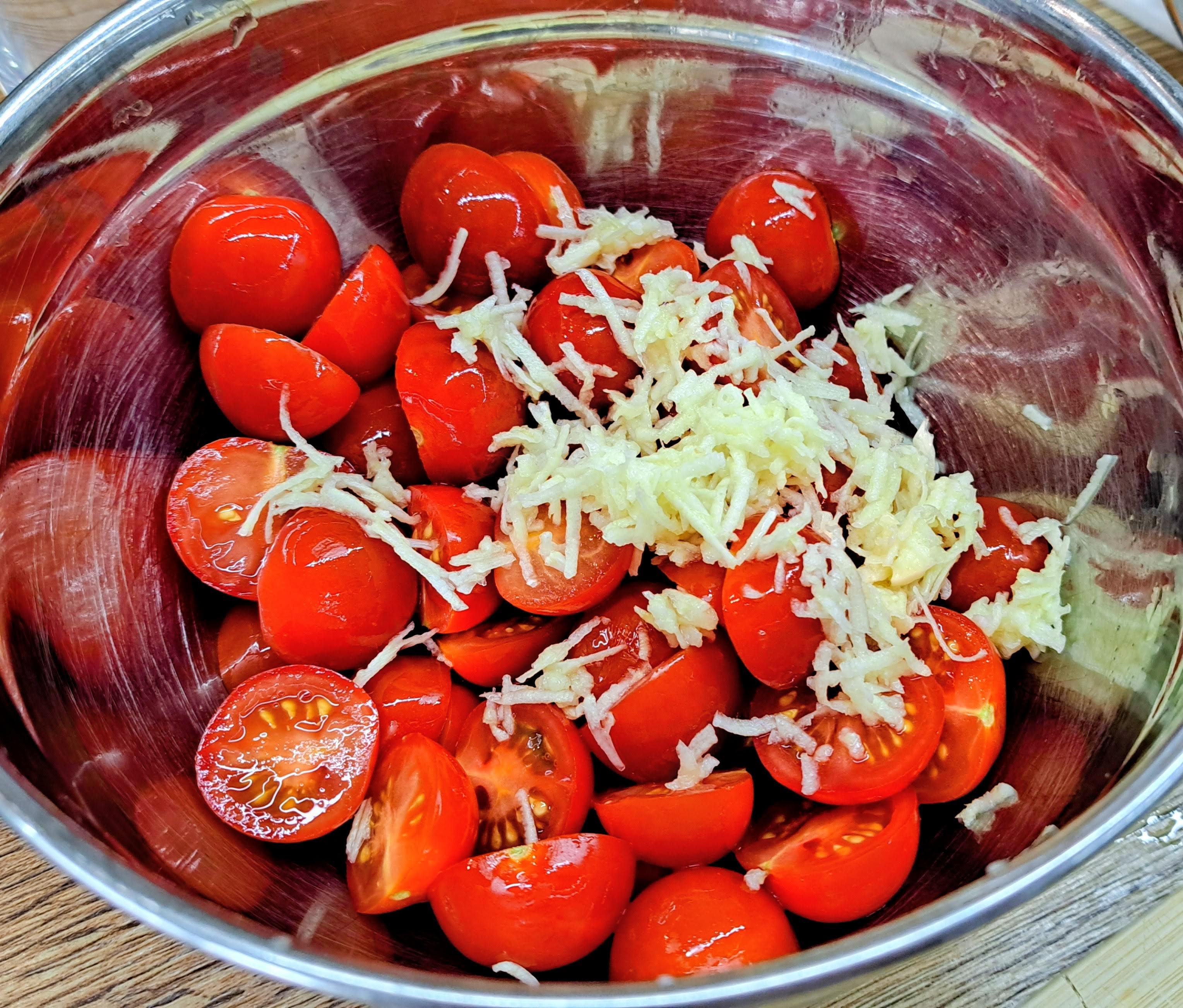 Cherry paradajky rozkrojíme na polovice, nastrúhame na nich 3 strúčiky cesnaku