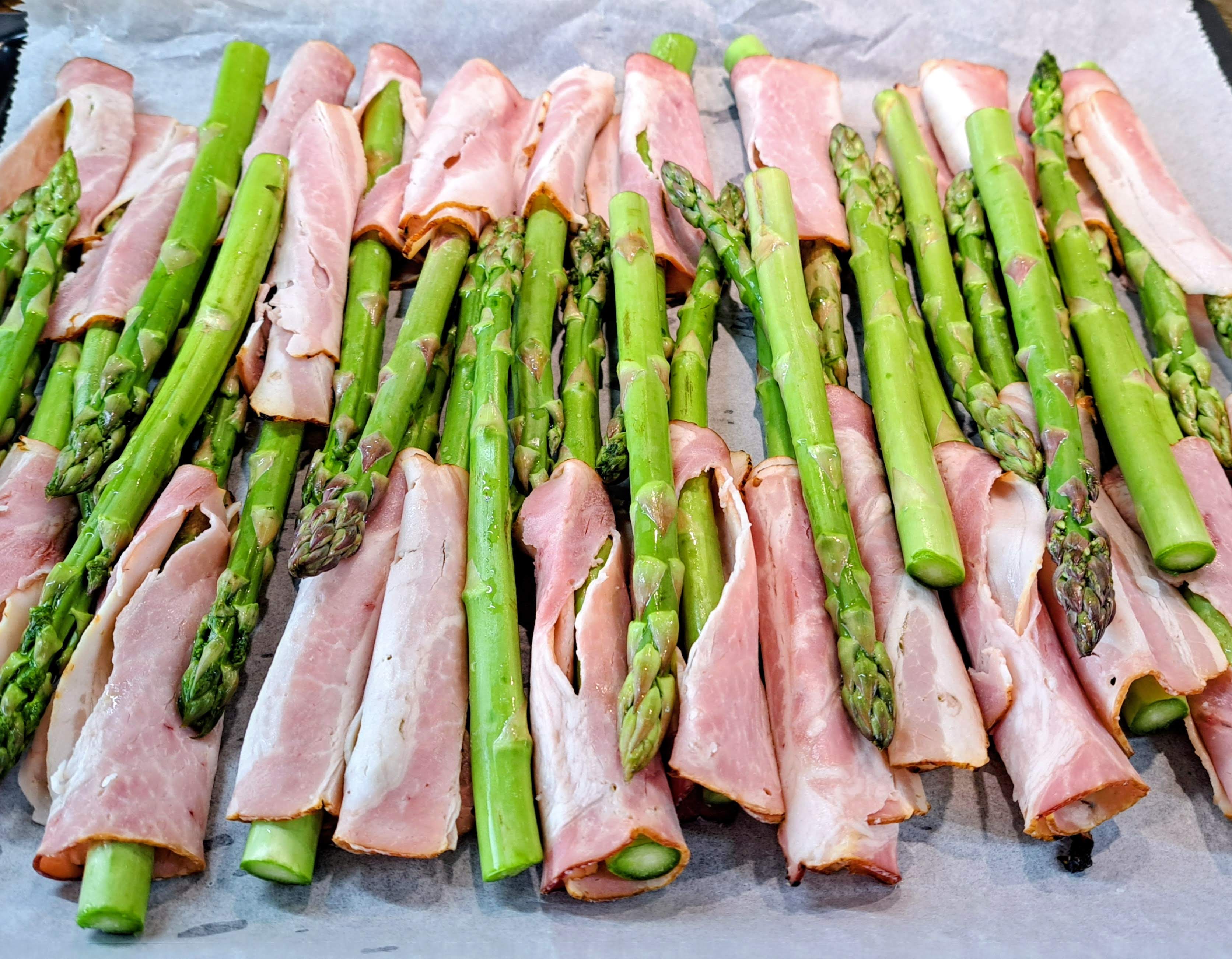 Špargľu obalíme plátkami anglickej slaniny a poukladáme ju na plech vystavený papierom na pečenie
