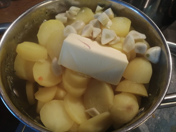 Na uvarené zemiaky pridáme maslo a konfitovaný cesnak